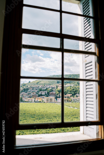 View from the window of a green lawn and ancient houses at the foot of the mountains