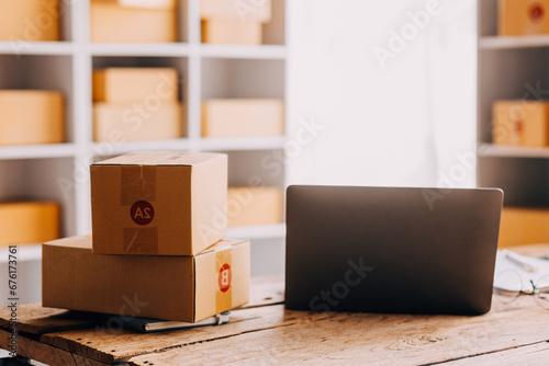 Startup SME small business entrepreneur of freelance Asian woman wearing apron using laptop and box to receive and review orders online to prepare to pack sell to customers, online sme business ideas. © ARMMY PICCA