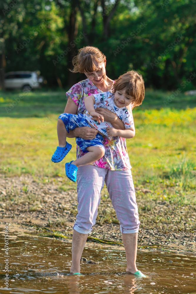 Fototapeta premium Grandson and grandmother playing on the river bank