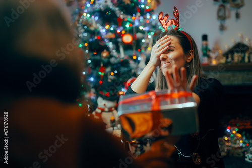 Ungrateful Woman Refusing a Christmas Gift from a Friend. Rude holiday party host rejecting presents from her guests 
 photo