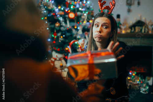 Ungrateful Woman Refusing a Christmas Gift from a Friend. Rude holiday party host rejecting presents from her guests 
 photo