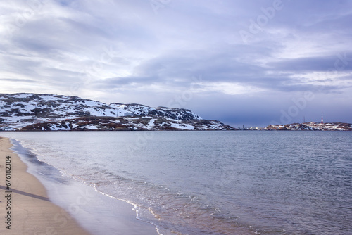 the shore of the Barents Sea in Teriberka sea and red mountains against the blue sky