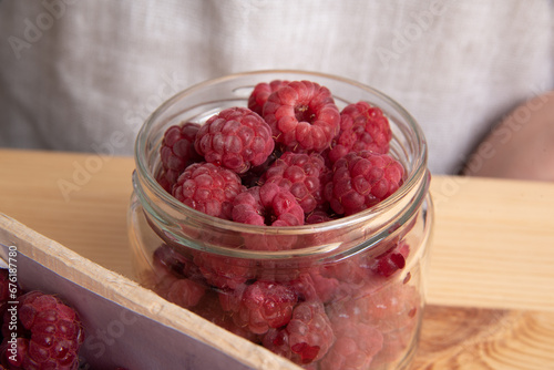 Processing raspberries for jam. Boxes of raspberries on a wooden table, next to the prepared forms for the preparation of blanks of compote and raspberry jam
