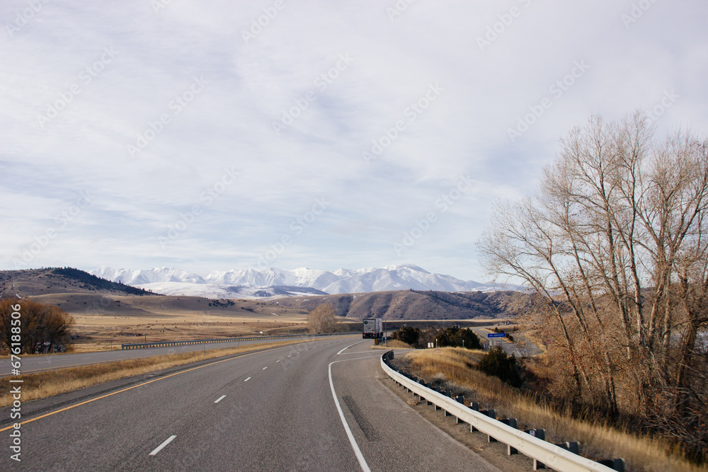 Beautiful landscape with a road among yellow dry grass and snow-covered mountains on the horizon. Beautiful landscape with a road among yellow dry grass and snow-covered mountains on the horizon.