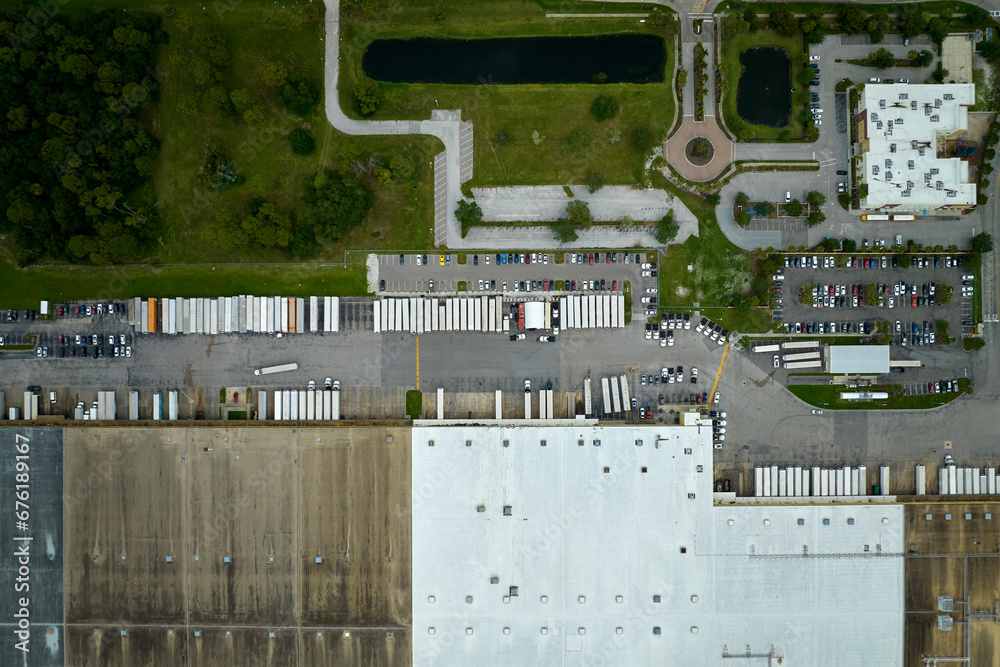 Aerial view of large commercial distribution center with many trucks unloading and uploading retail products for further shipment. Global economy concept Aerial view of large commercial distribution center with many trucks unloading and uploading retail products for further shipment. Global economy concept
