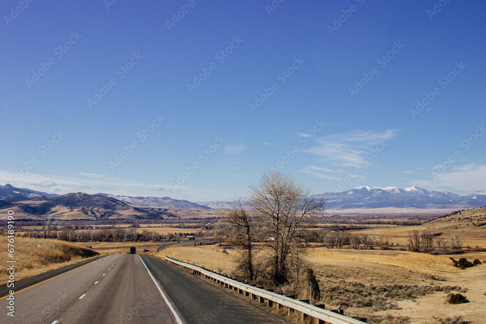 Beautiful landscape with a road among yellow dry grass and snow-covered mountains on the horizon. Beautiful landscape with a road among yellow dry grass and snow-covered mountains on the horizon.