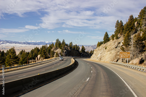 Steep highway in the mountains among huge rocks and high mountains on the horizon on a sunny day. Beautiful blue sky with clouds over mountains and asphalt road. USA highways © Liudmila