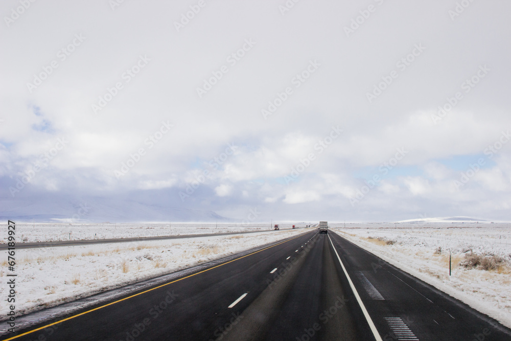 Steep highway among snow-capped mountains on a sunny winter day. Bright blue winter sky with large clouds over an asphalt road. Highways in USA. American roads Steep highway among snow-capped mountains on a sunny winter day. Bright blue winter sky with large clouds over an asphalt road. Highways in USA. American roads