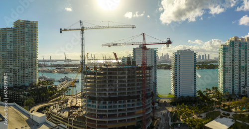 Tower lifting cranes at high residential apartment building construction site. Real estate development in Miami urban area