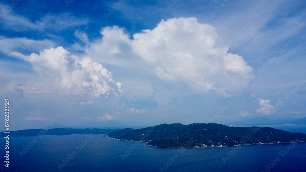 White clouds over a tropical island. Large cumulus clouds over a tropical island and blue sea.