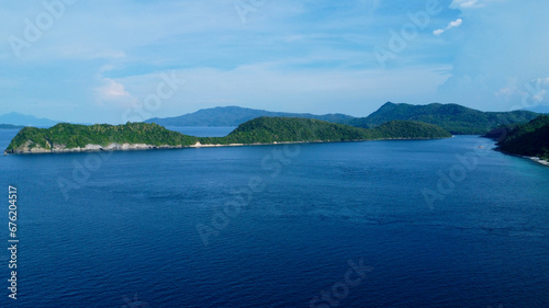 Tropical island covered with jungle. Aerial view of the hilly coast of a tropical island on the horizon.