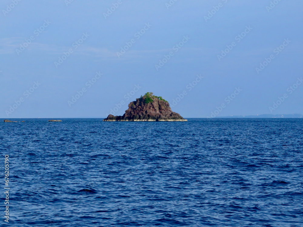 Island in the ocean. A small rocky island in the middle of the sea. Island in the ocean. A small rocky island in the middle of the sea.