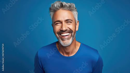Happy ultra handsome Caucasian middle aged man, smiling and laughing, wearing a Bright solid blue shirt
