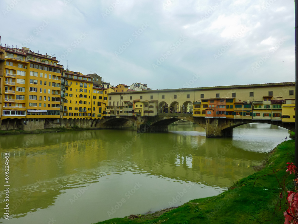 Scenic view of historic medieval Ponte Vecchio bridge with shops spanning the Arno River, Florence, Tuscany, Italy, Europe. Landmark in Italian city on cloudy overcast day. Tourist travel destination