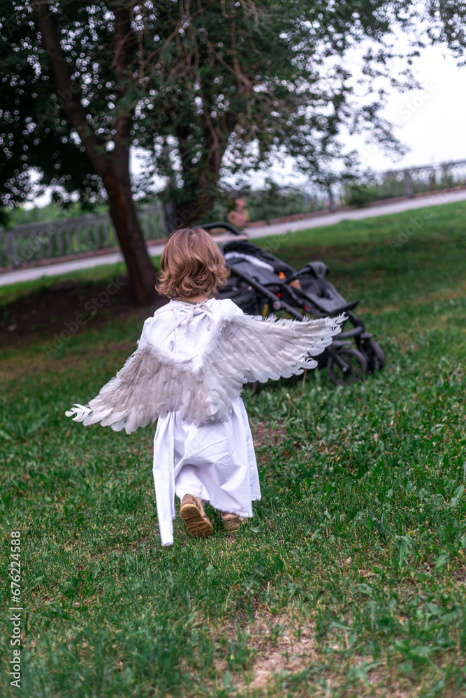 little boy in a city park dressed as an angel little boy in a city park dressed as an angel