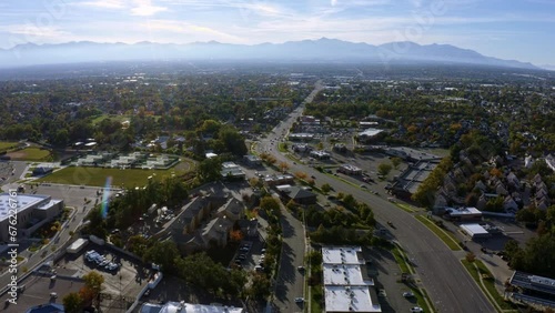 Dolly in tilt up aerial drone extreme wide landscape shot of the Salt Lake county valley covered in buildings, busy roads, and colorful autumn trees surrounded by mountains on a fall evening in Utah photo