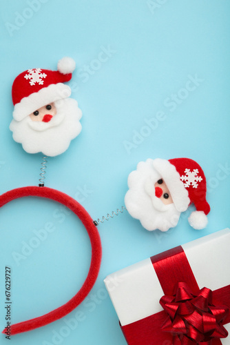 Christmas headband Santa Claus head design with white gift with red bow on blue background.