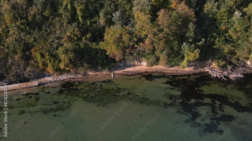 A man on the coast of the sea in a wilderness is signaling for help with a signal mirror A man on the coast of the sea in a wilderness is signaling for help with a signal mirror