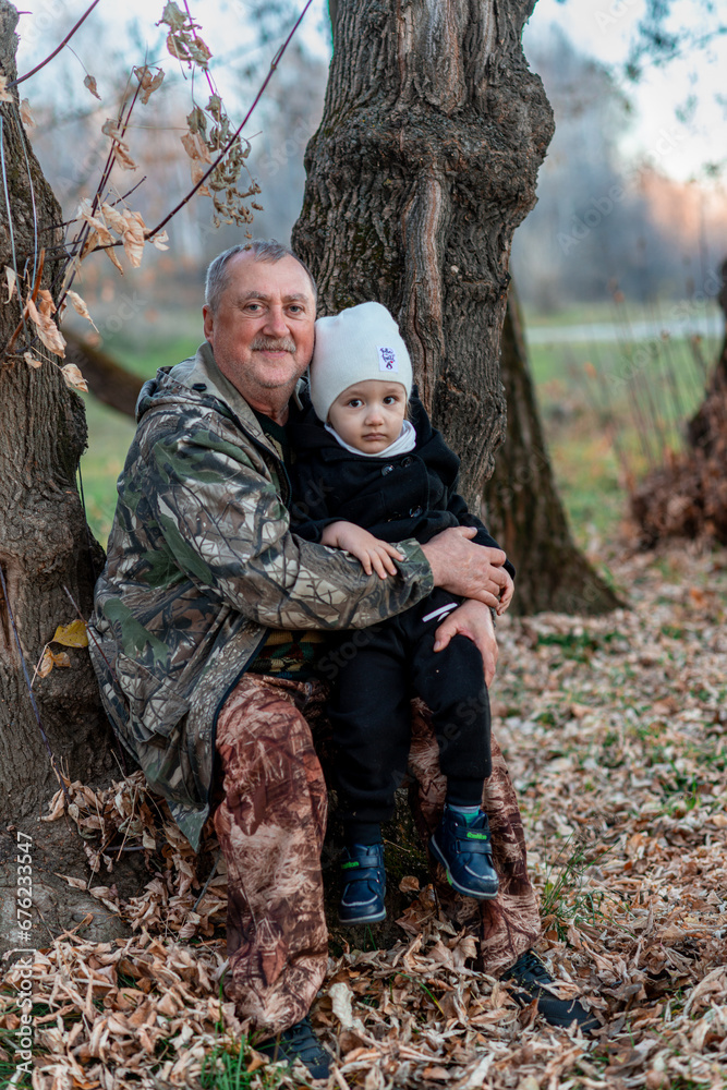 little boy in the autumn forest with his grandparents