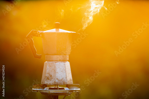 Moka pot and smoke, Steam from the coffee pot on fire, In the forest at sunrise in the morning. soft focus. shallow focus effect. photo