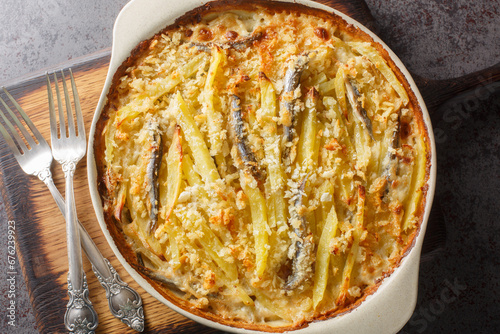 Homemade Jansson's temptation made from potatoes, onion and sprats closeup on the baking dish on the table. Horizontal top view from above photo