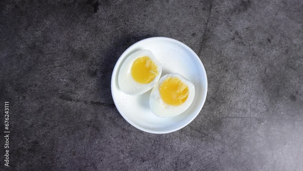 Two halves of a boiled egg lie on a white saucer. View from above. Two halves of a boiled egg lie on a white saucer. View from above.
