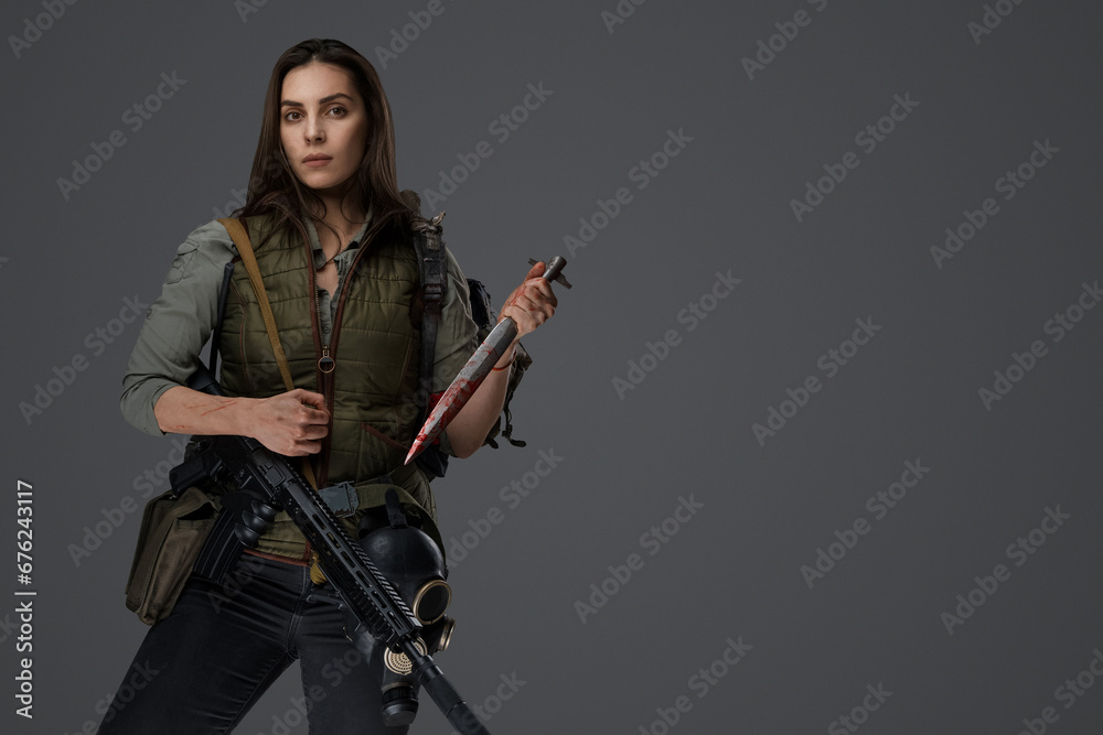 Middle Eastern-looking woman dressed in survivalist clothing posing with a rifle against a gray background, portraying strength and resilience Middle Eastern-looking woman dressed in survivalist clothing posing with a rifle against a gray background, portraying strength and resilience