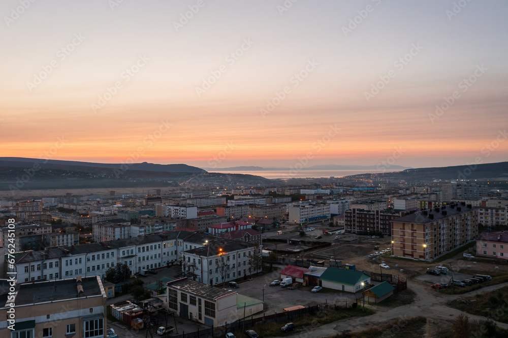 Morning cityscape. Aerial view of the city at dawn. Top view of buildings. In the distance is a sea bay. Early morning. City of Magadan, Magadan region, Siberia, Far East of Russia.