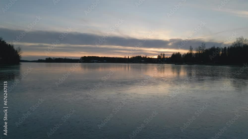 Sunset reflecting on frozen lake in Sweden, dolly forward view