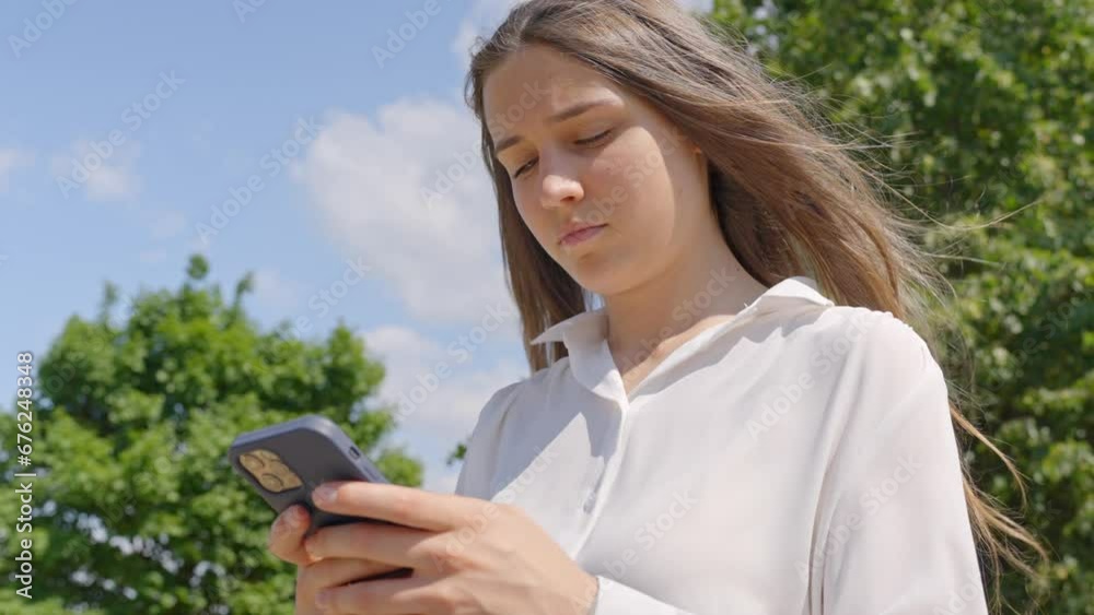 Classy brunette with serious look checking smartphone on sunny day Classy brunette with serious look checking smartphone on sunny day