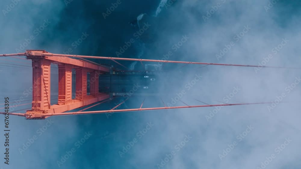 Aerial of red Golden Gate bridge. Busy road of red bridge over deep blue Pacific Ocean waters. Top down fog drifting around industrial architecture construction in San Francisco bay, California USA 4K