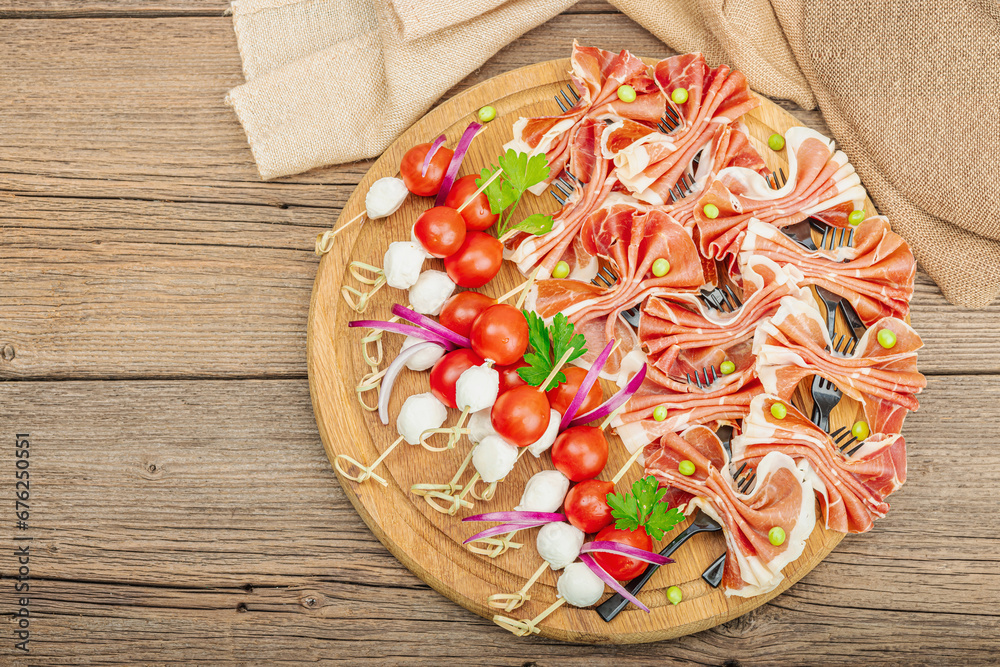 Set of picnic snacks on skewers. Jamon, mozzarella, cherry tomatoes, peas, fresh greens Set of picnic snacks on skewers. Jamon, mozzarella, cherry tomatoes, peas, fresh greens