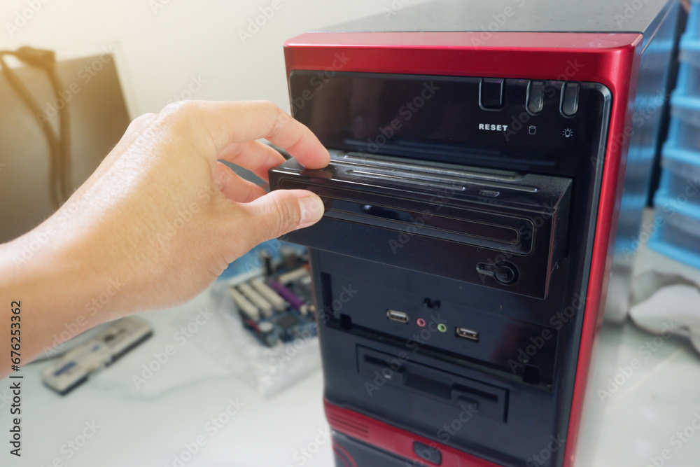 Man's hand inserting CD-ROM into computer case Man's hand inserting CD-ROM into computer case