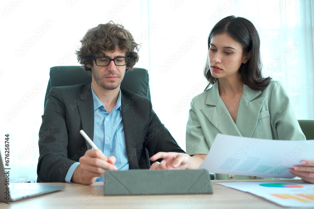 Asian businessman and businesswoman talking together in an office, a businessman talking or discussing with his female secretary about the business project on laptop - notebook computer screen. Asian businessman and businesswoman talking together in an office, a businessman talking or discussing with his female secretary about the business project on laptop - notebook computer screen.