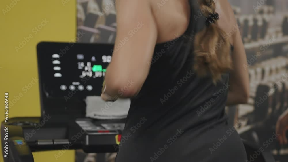 A Young Woman is Exercising on a Treadmill. Her Hair is in a Braid. A Young Woman is Exercising on a Treadmill. Her Hair is in a Braid.