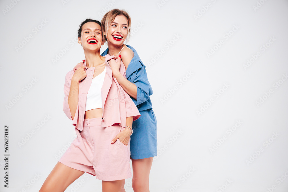Two young beautiful smiling brunette hipster female in trendy summer clothes. Sexy carefree women posing on white background in studio. Positive models having fun. Cheerful and happy. Isolated Two young beautiful smiling brunette hipster female in trendy summer clothes. Sexy carefree women posing on white background in studio. Positive models having fun. Cheerful and happy. Isolated