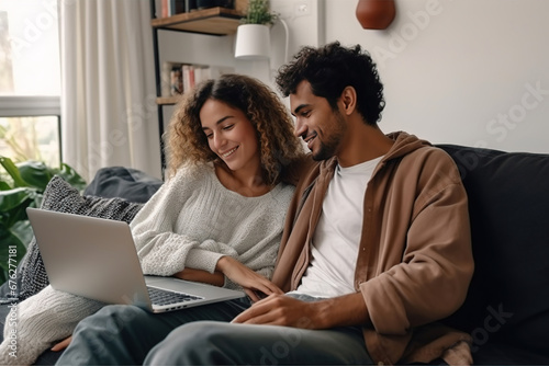 Multiracial young couple watching computer laptop sitting on the sofa at home - Happy diverse husband and wife using pc online services - Technology life style concept photo