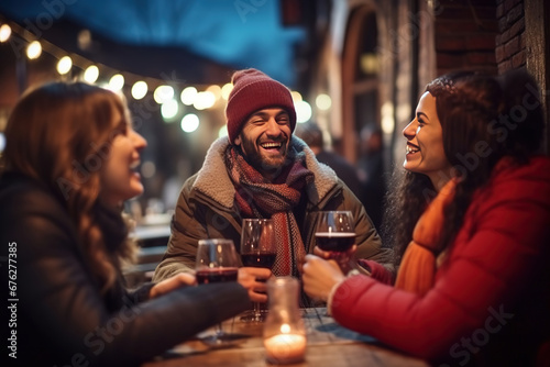 Happy multiracial friends toasting red wine at restaurant terrace - Group of young people wearing winter clothes having fun at outdoors winebar table - Dining life style and friendship concept