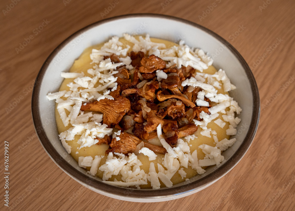 Tasty banosh served with brynza and mushrooms in bowl on table, top view. Traditional Ukrainian dish Tasty banosh served with brynza and mushrooms in bowl on table, top view. Traditional Ukrainian dish