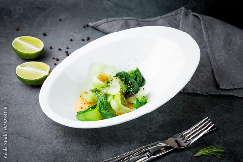 bok choy cabbage with sesame seeds and sauce in a white plate, top view photo