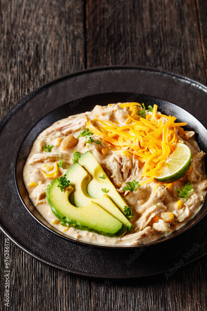 white chicken chili with cheese, avocado in bowl white chicken chili with cheese, avocado in bowl