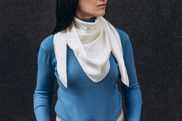 White silk scarf on woman's neck on dark grey background. Lifestyle.