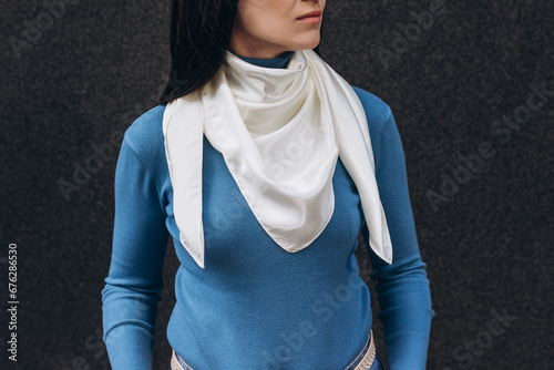 White silk scarf on woman's neck on dark grey background. Lifestyle.