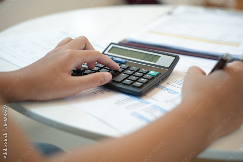 Businesswoman Accountant analyzing investment charts Invoice and pressing calculator buttons over documents. Accounting Bookkeeper Clerk Bank Advisor And Auditor Concept. Businesswoman Accountant analyzing investment charts Invoice and pressing calculator buttons over documents. Accounting Bookkeeper Clerk Bank Advisor And Auditor Concept.