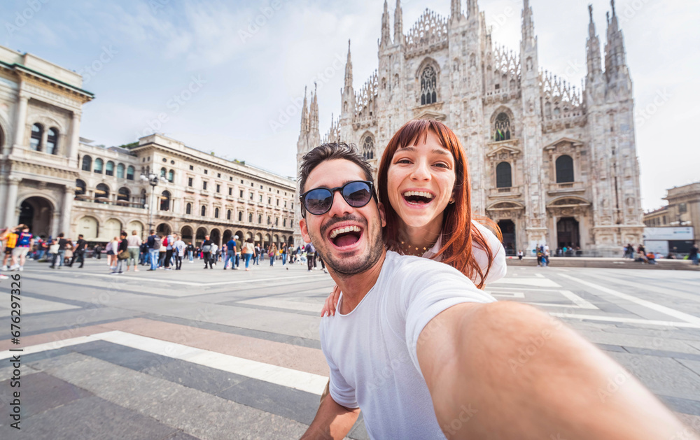 Happy couple taking selfie in front of Duomo cathedral in Milan, Lombardia - Two tourists having fun on romantic summer vacation in Italy - Holidays and traveling lifestyle concept - obrazy, fototapety, plakaty 