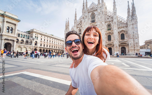 Happy couple taking selfie in front of Duomo cathedral in Milan, Lombardia - Two tourists having fun on romantic summer vacation in Italy - Holidays and traveling lifestyle concept photo