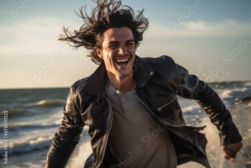 n image of a young, handsome man, embracing the liberating feeling of joy as he runs along the beach, the wind tousling his hair photo