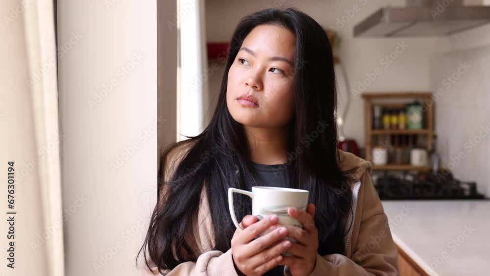 Young beautiful woman with a mug drinking coffee next to a window in a kitchen. Smiling woman enjoying a coffee break at home. Young beautiful woman with a mug drinking coffee next to a window in a kitchen. Smiling woman enjoying a coffee break at home.