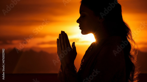 Woman, silhouette and meditation in nature at sunset or sunrise, for mindfulness and spirituality worship. Prayer hands, peaceful and religion practise with view for mental health, zen and stress fre