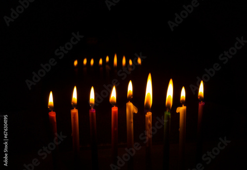 Hanukkah Menorah with eight lit colored candles and one additional, intended for Hanukkah, a Jewish holiday, the traditional festival of lights. On the window with reflection.
free space for text